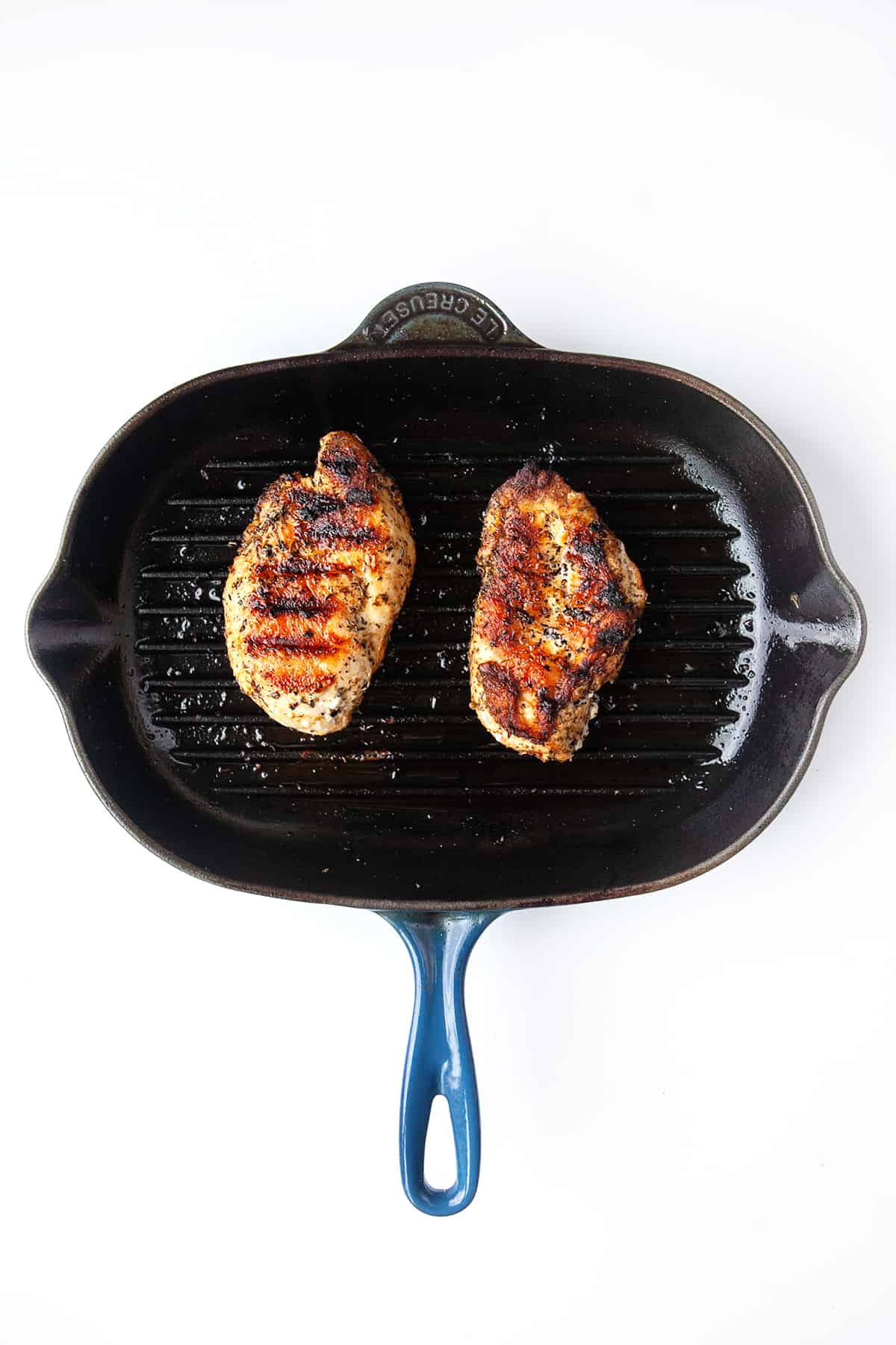 Two chicken breasts in a grill pan from overhead. 