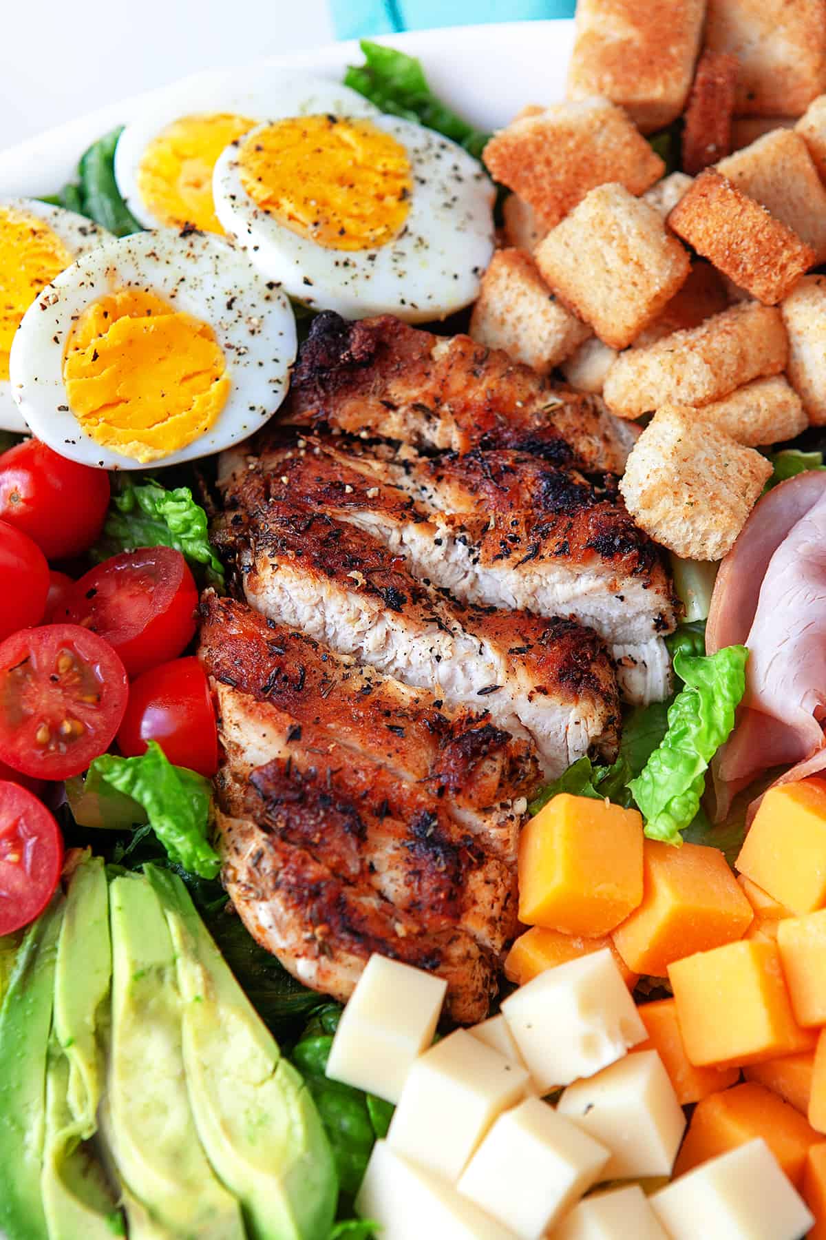 Close-up of chef salad in a bowl from overhead, mainly showing the chicken breast. 