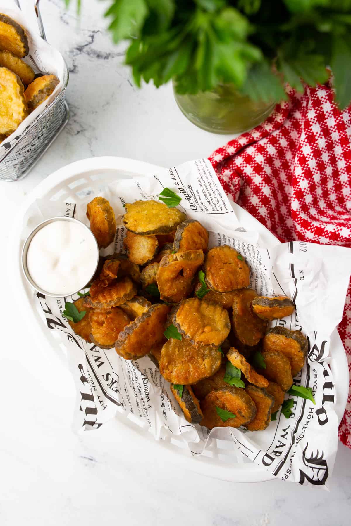 A basket of deep fried pickle chips served with ranch and garnished with parsley.
