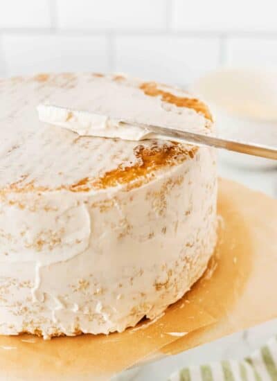 Putting a crumb coat of icing on the top of a cake.