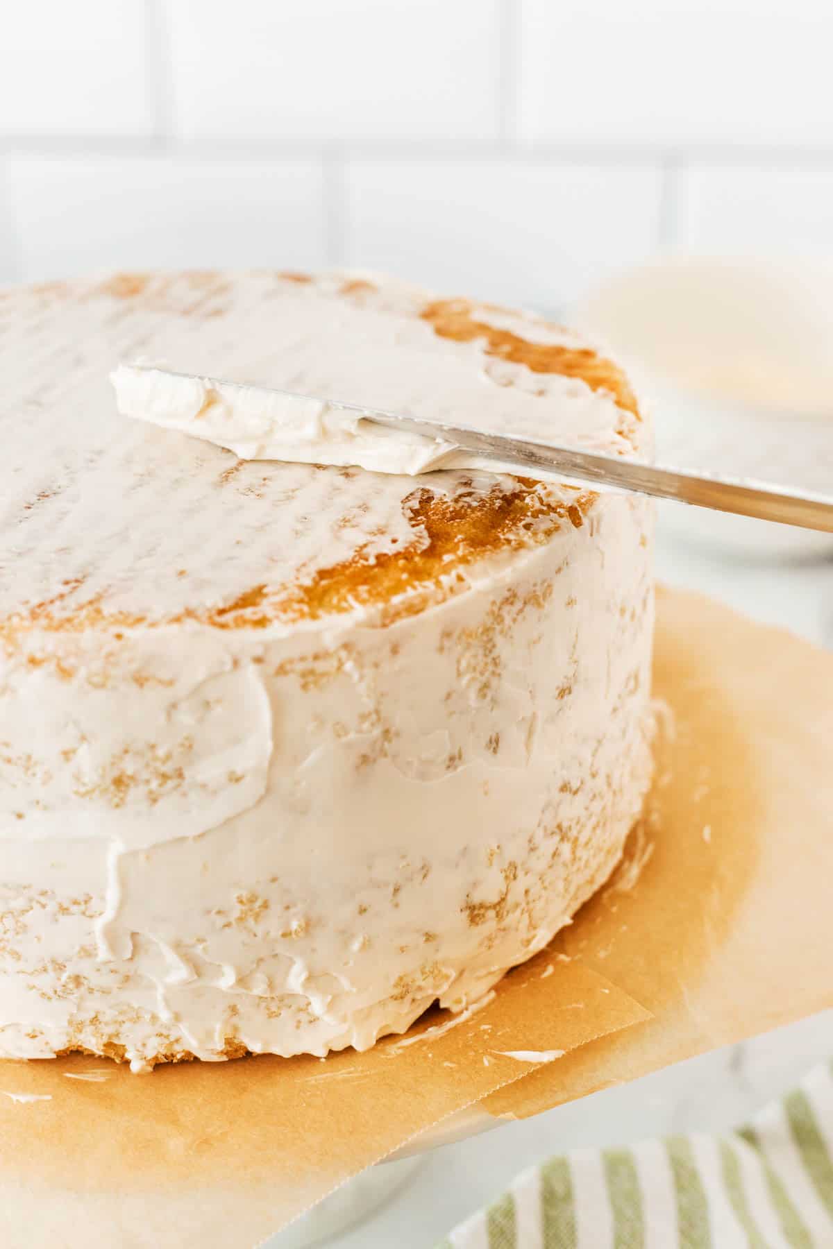 Putting a crumb coat of icing on the top of a cake. 