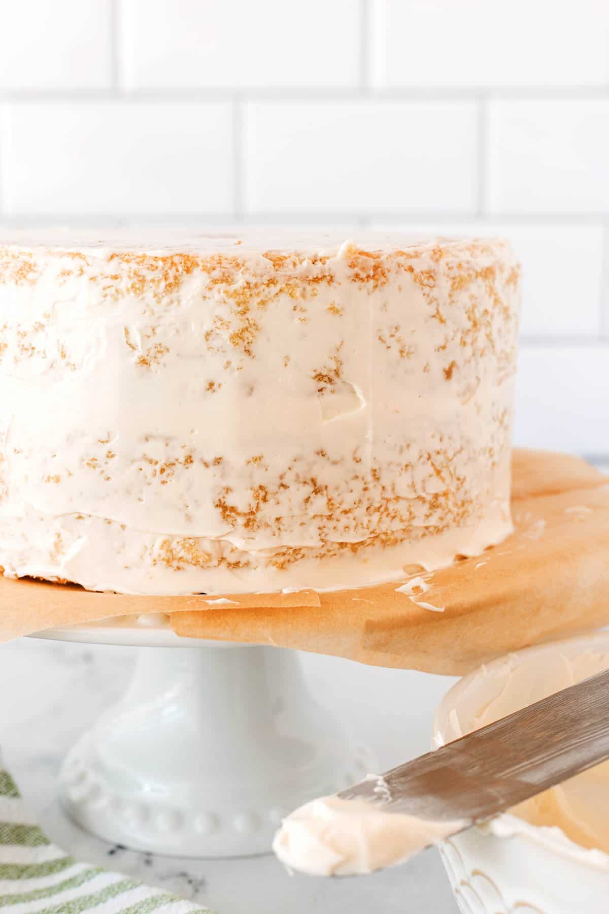 A cake with a crumb coat of icing. 