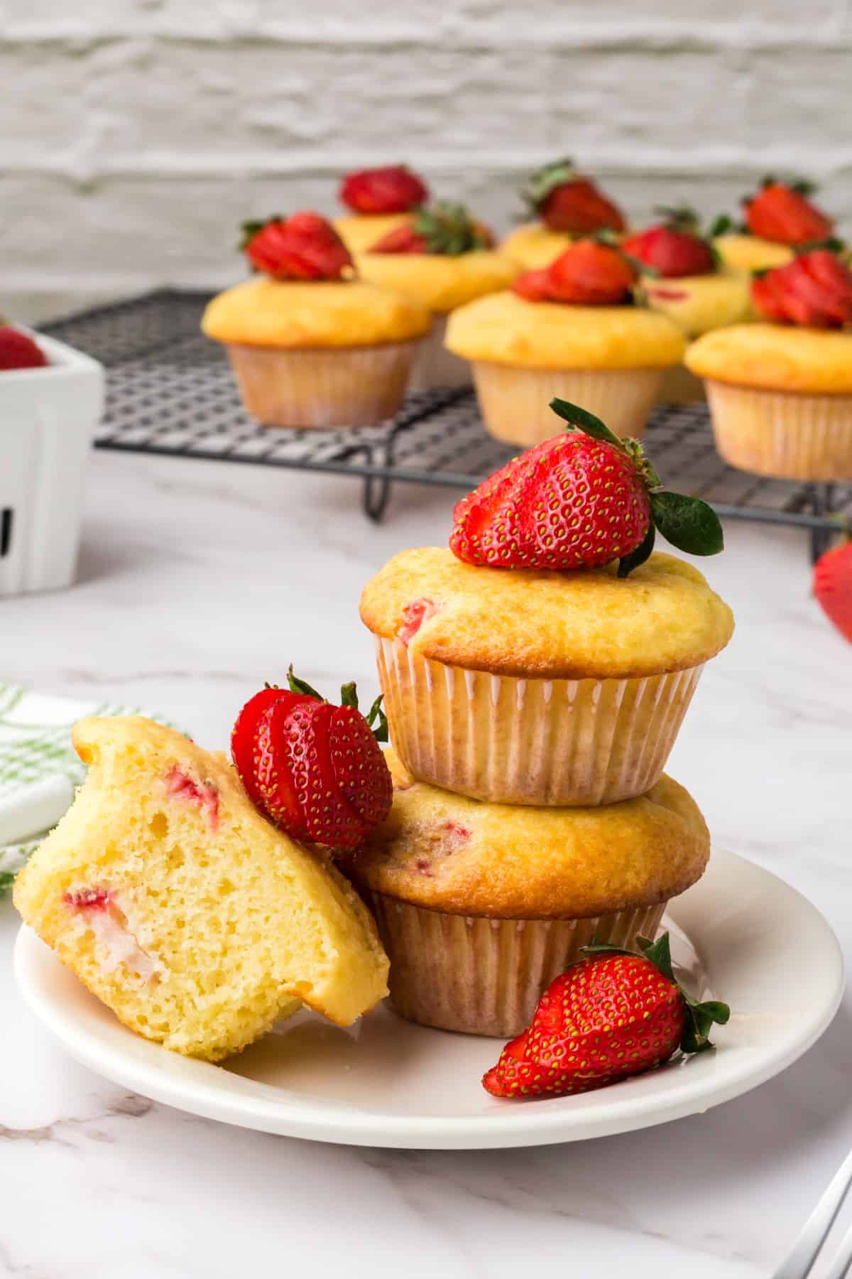 Muffins and strawberries stacked with one muffin sliced in half. 