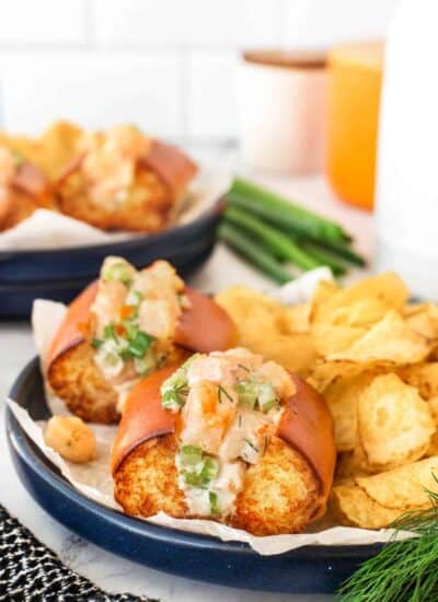 Shrimp rolls on a blue plate with kettle chips.