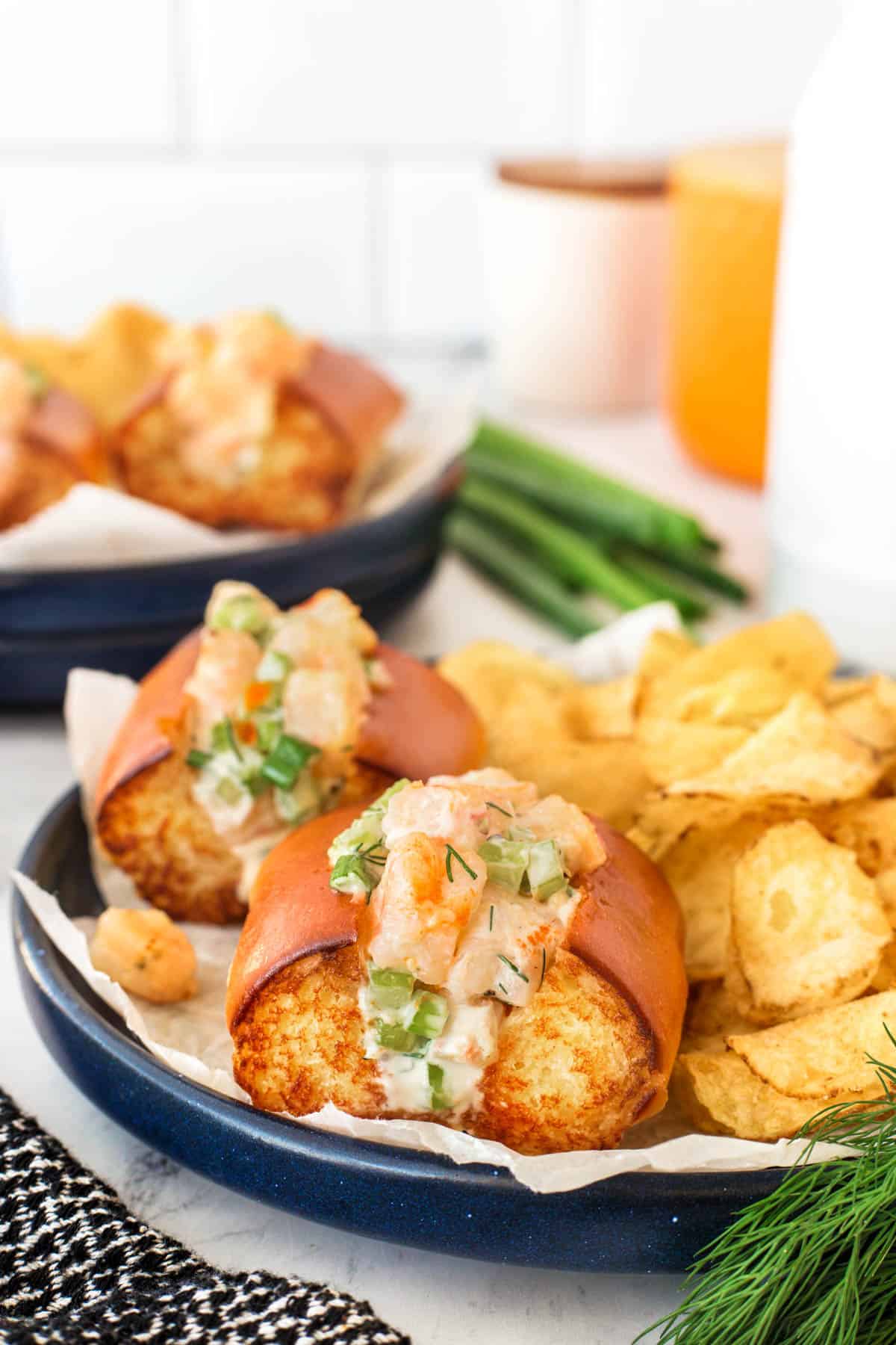 Shrimp rolls on a blue plate with kettle chips. 