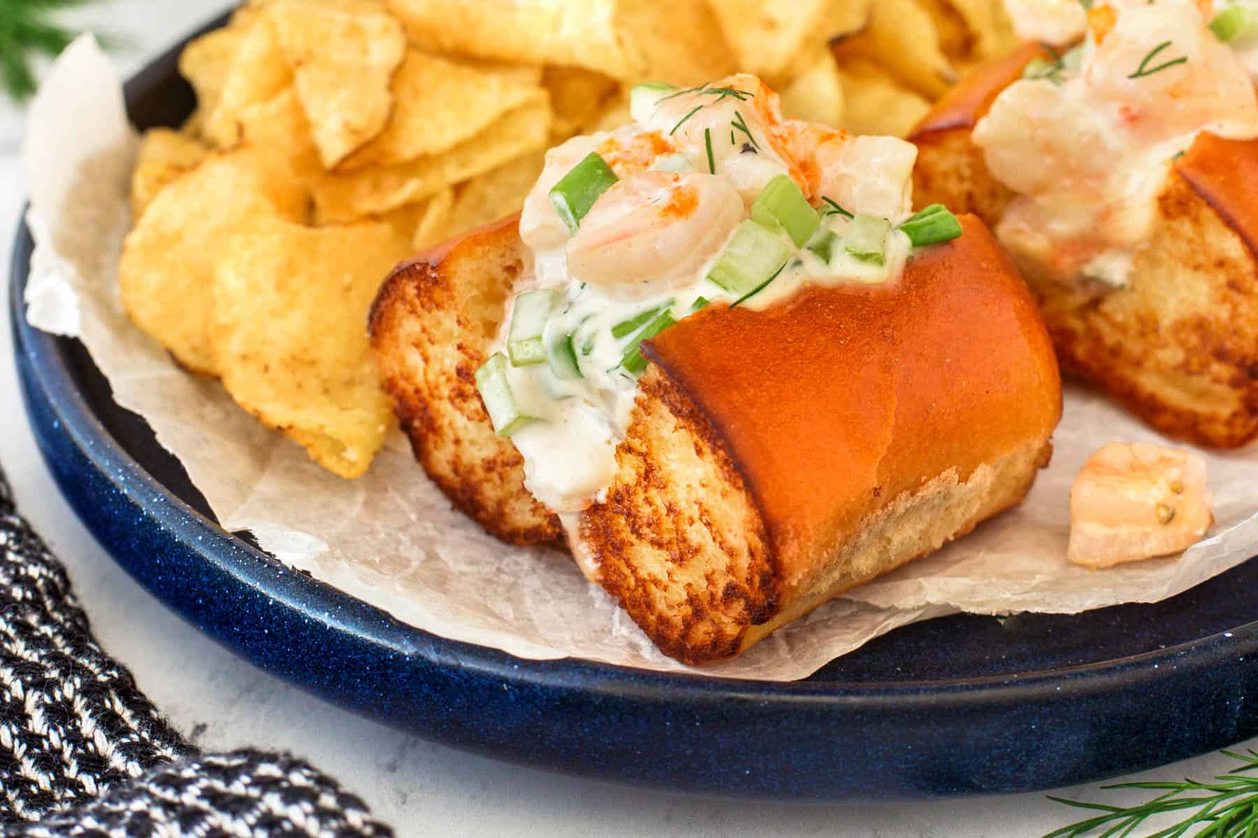 Shrimp roll on a plate with chips. 