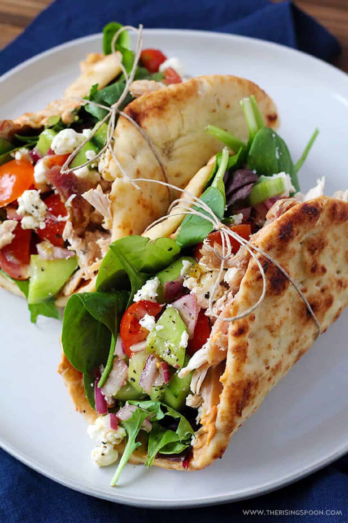 Two chicken hummus naan wraps tied with string. 