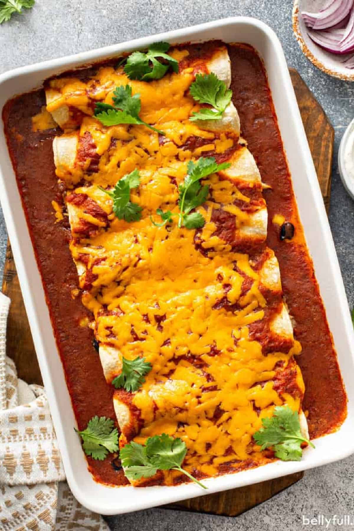 Chicken enchiladas covered in melted cheddar cheese in baking dish