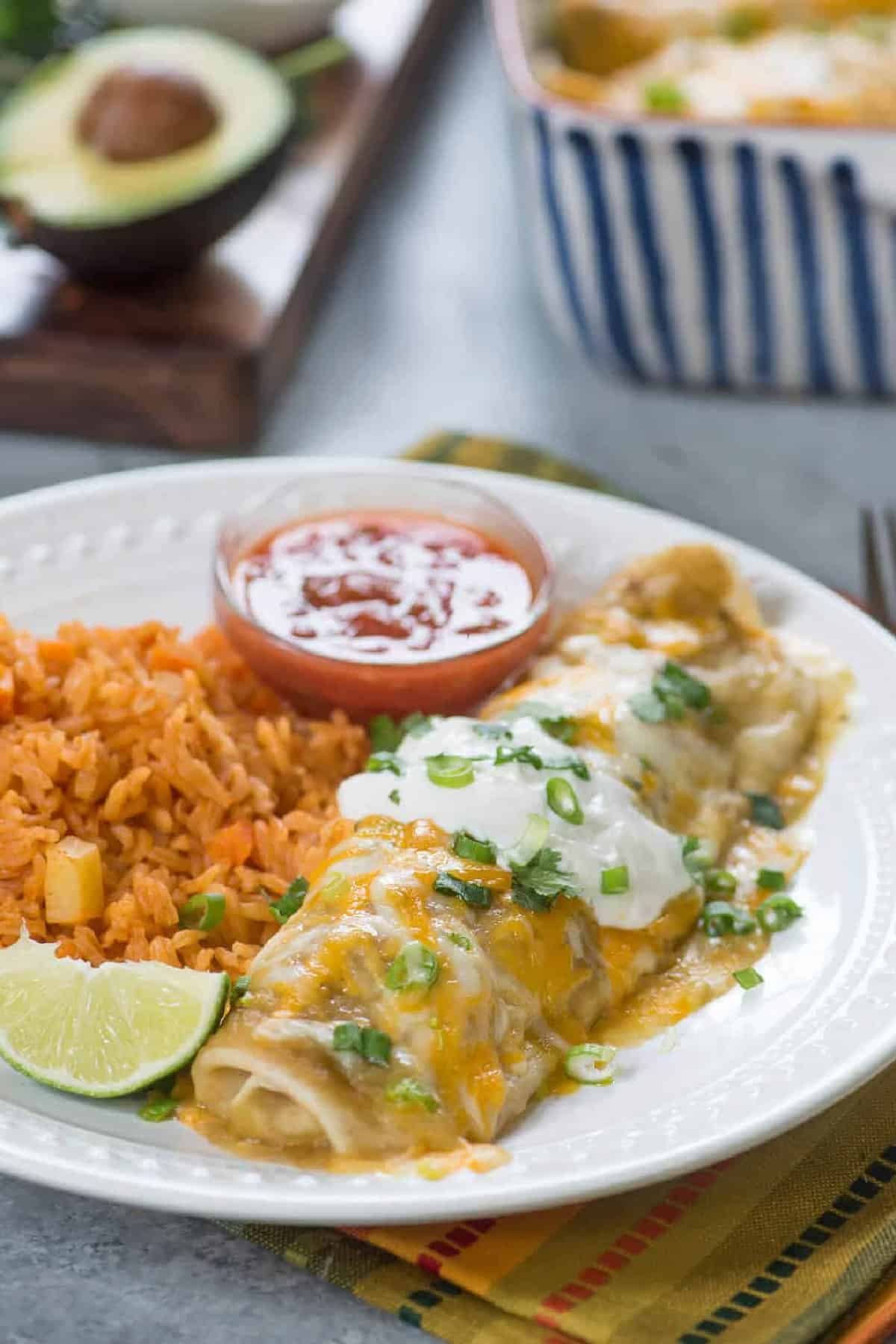 Green Chile Chicken Smothered Burritos with rice, salsa and a slice of lime. 