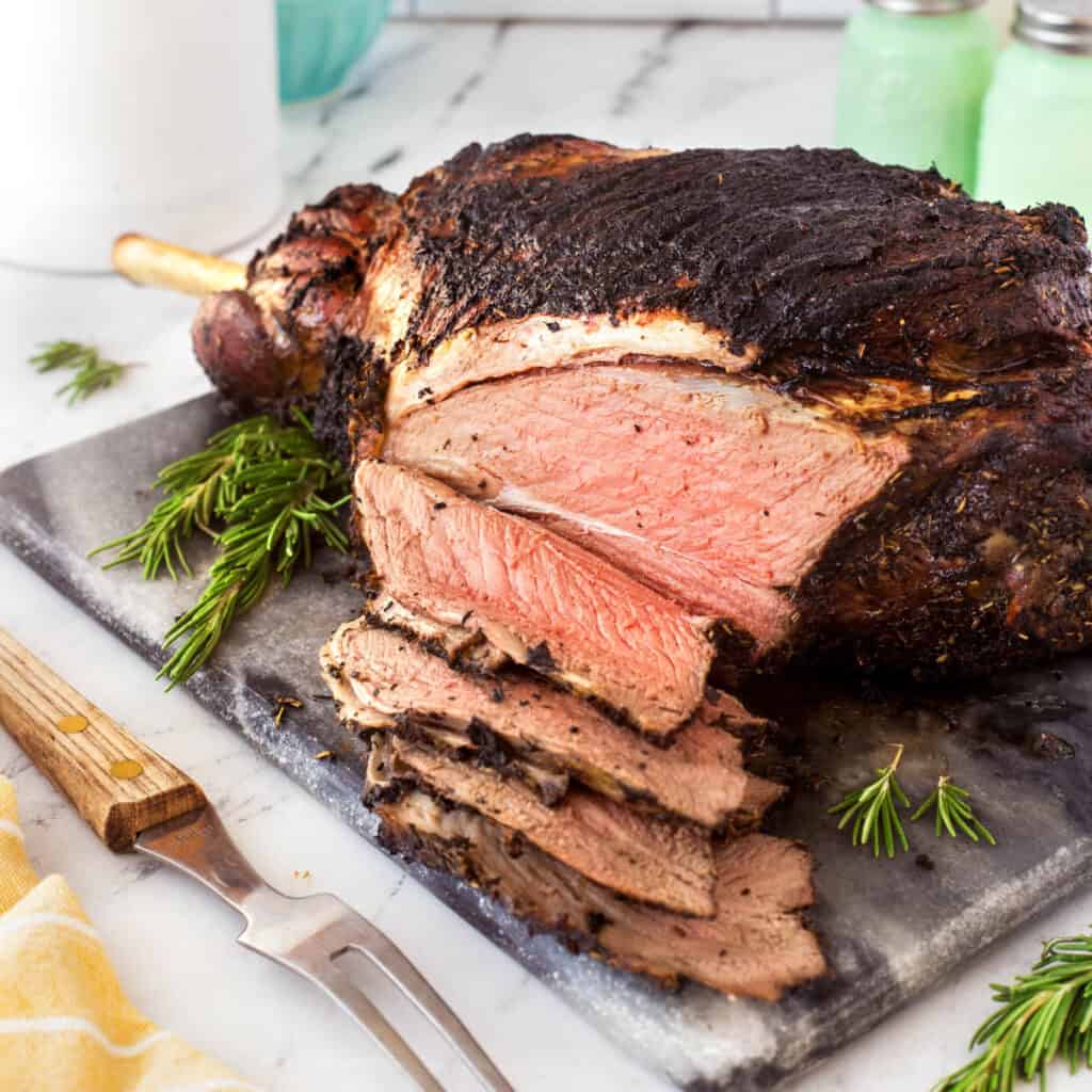 Square photo of lamb sliced on a cutting board off the roast. 