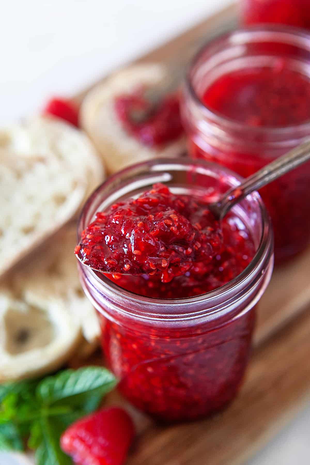 Taking a spoonful of raspberry jam from a jar. 