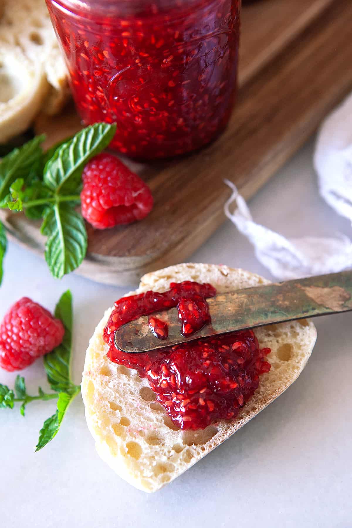 Spreading raspberry jam on an English muffin. 