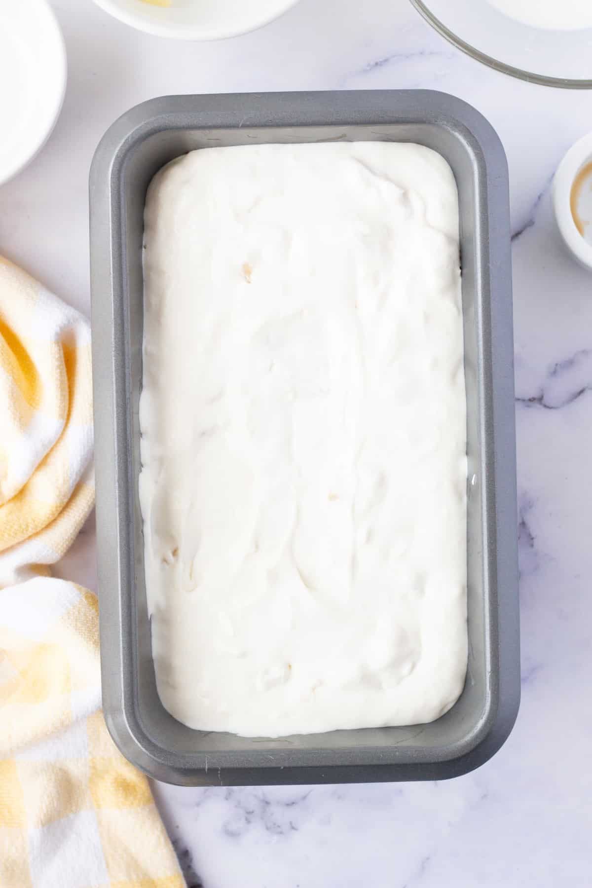 Overhead of a loaf pan filled with ice cream.