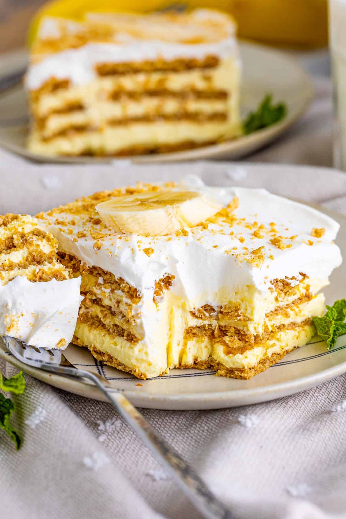 A serving of Banana Icebox Cake on a plate with a forkful on the side. 