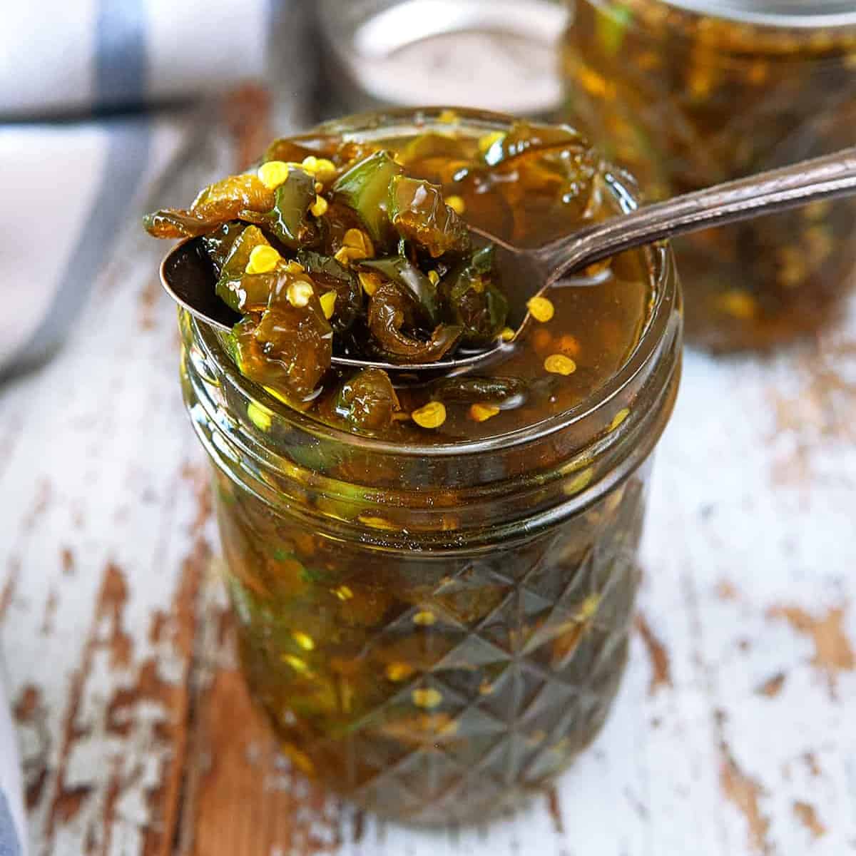 Taking a spoonful of candied jalapenos from a jar