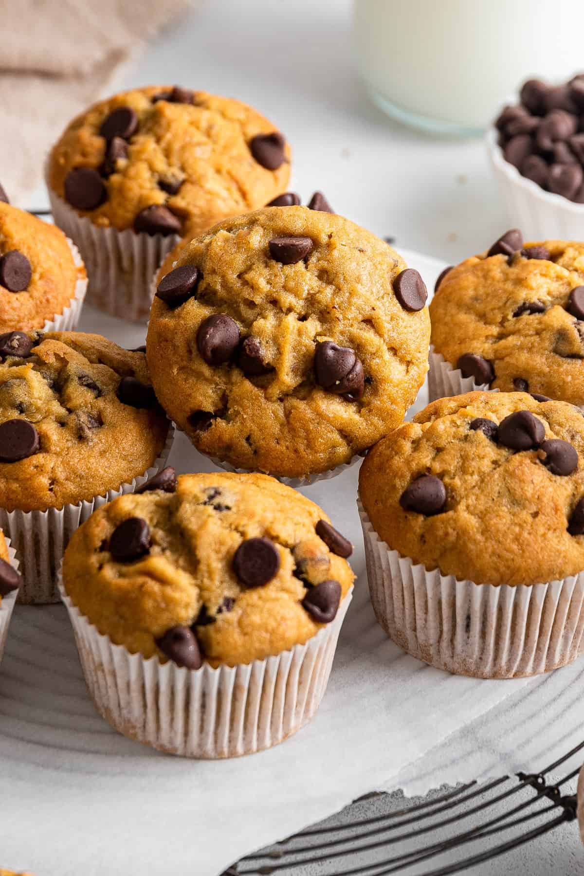 Banana Chocolate Chip Muffins on a cooling rack with one tilted forward. 