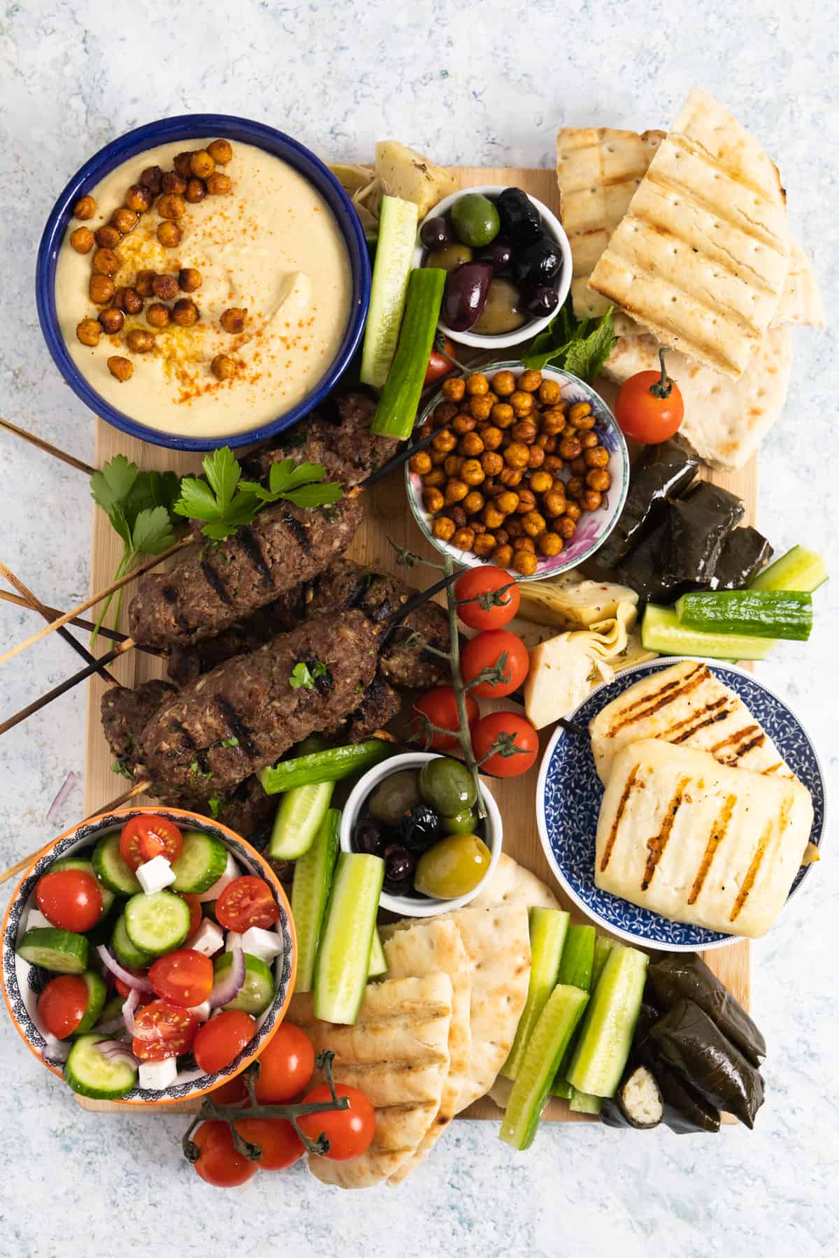 Top view of a mezze platter with kofta, pita, hummus, halloumi.