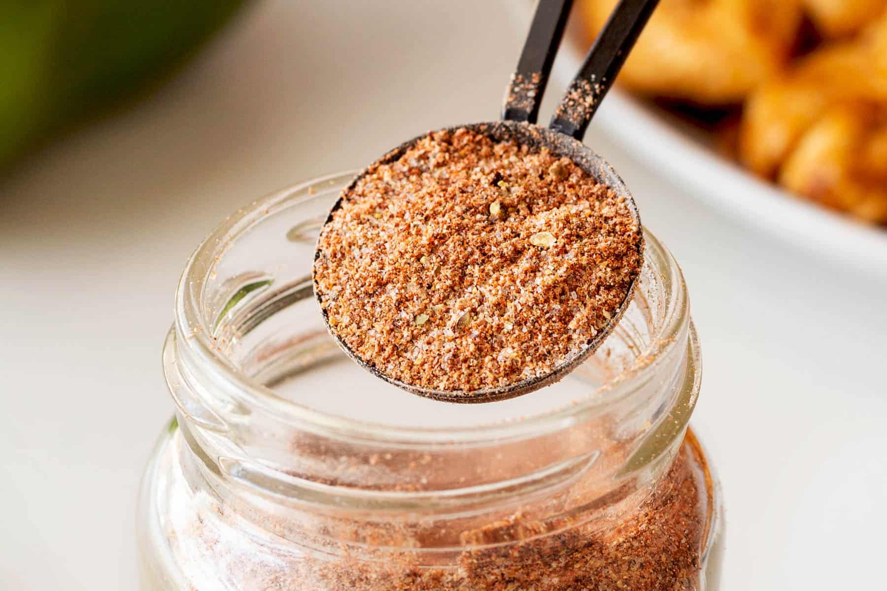 Horizontal picture of scooping out a tablespoon of seasoning from a jar. 