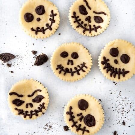 Overhead shot of different faces of Jack Skellington on mini cheesecakes.