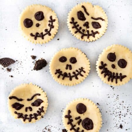 Overhead picture of Jack Skellington Halloween Cheesecakes with different faces.