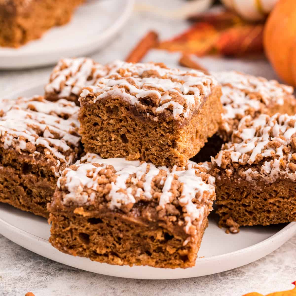 Square photo of squares of pumpkin coffee cake on a plate. 