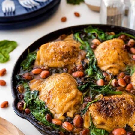 Close-up shot of Chicken Skillet with Beans and Greens in a cast iron pan.