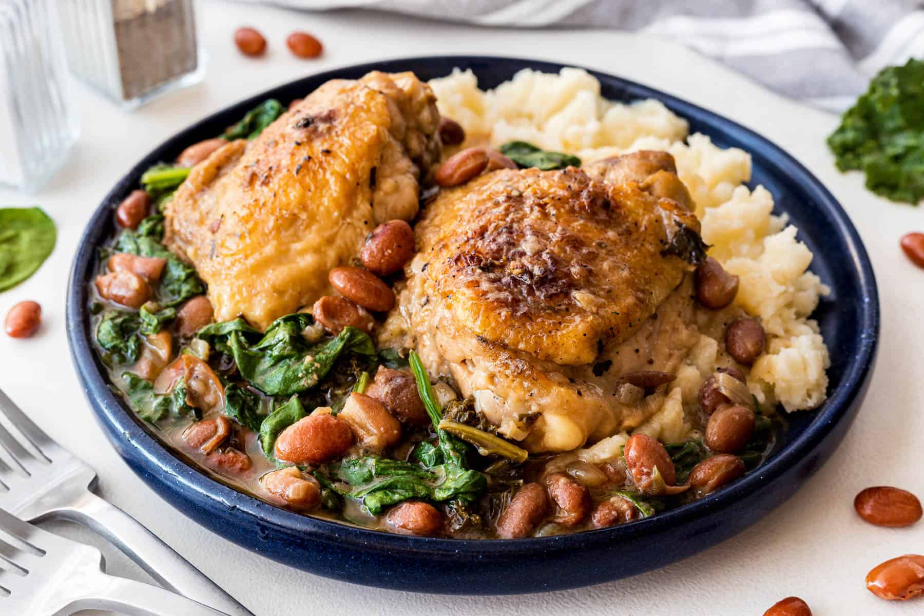 Chicken thighs with beans and greens over mashed potatoes. 