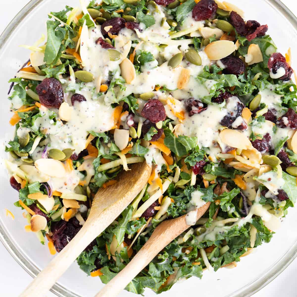 Overhead shot of sweet kale salad in a bowl with tongs