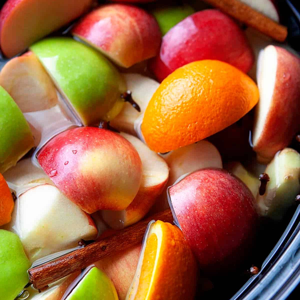 Overhead close-up of apples, oranges and spices in a crock-pot. 