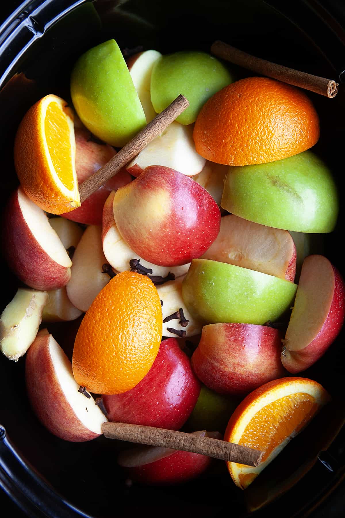 Apples, oranges, and spices in a slow cooker but no water. 