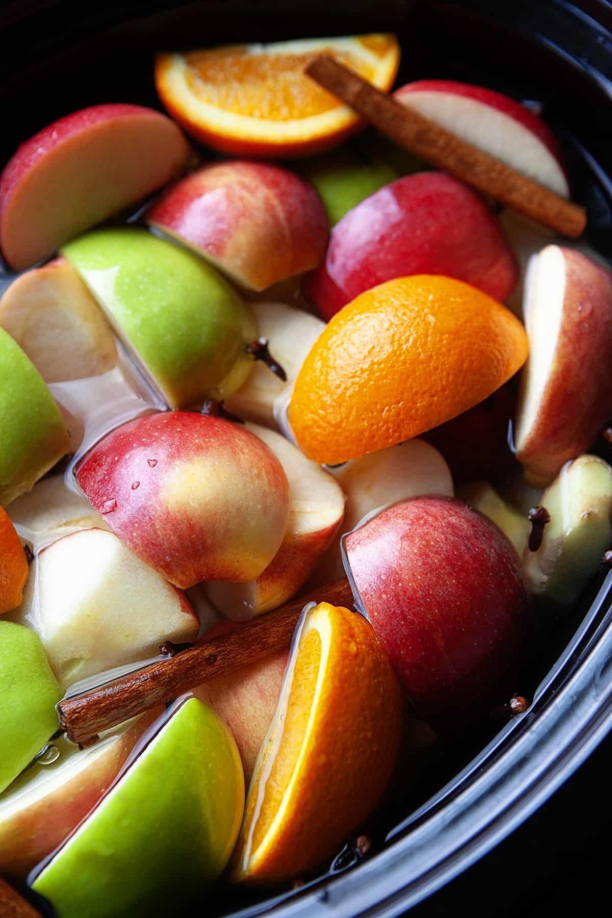 Apples, oranges, spices and water in a slow cooker. 