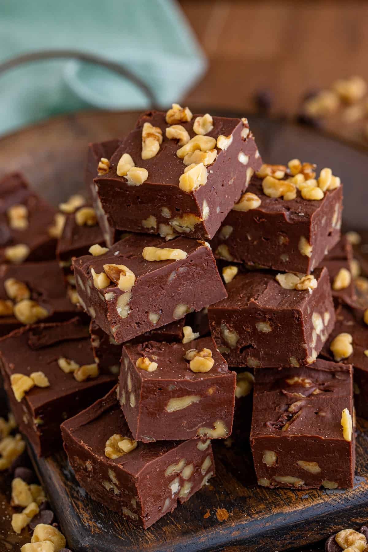 Easy chocolate walnut fudge squares stacked on a wooden board.