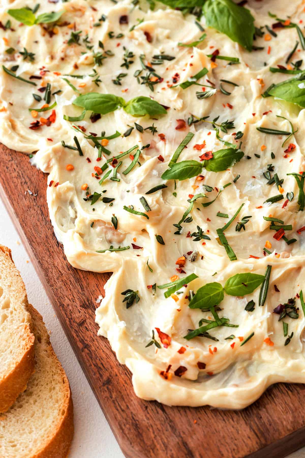 Close-up of a butter board with fresh herbs and red pepper flakes. 