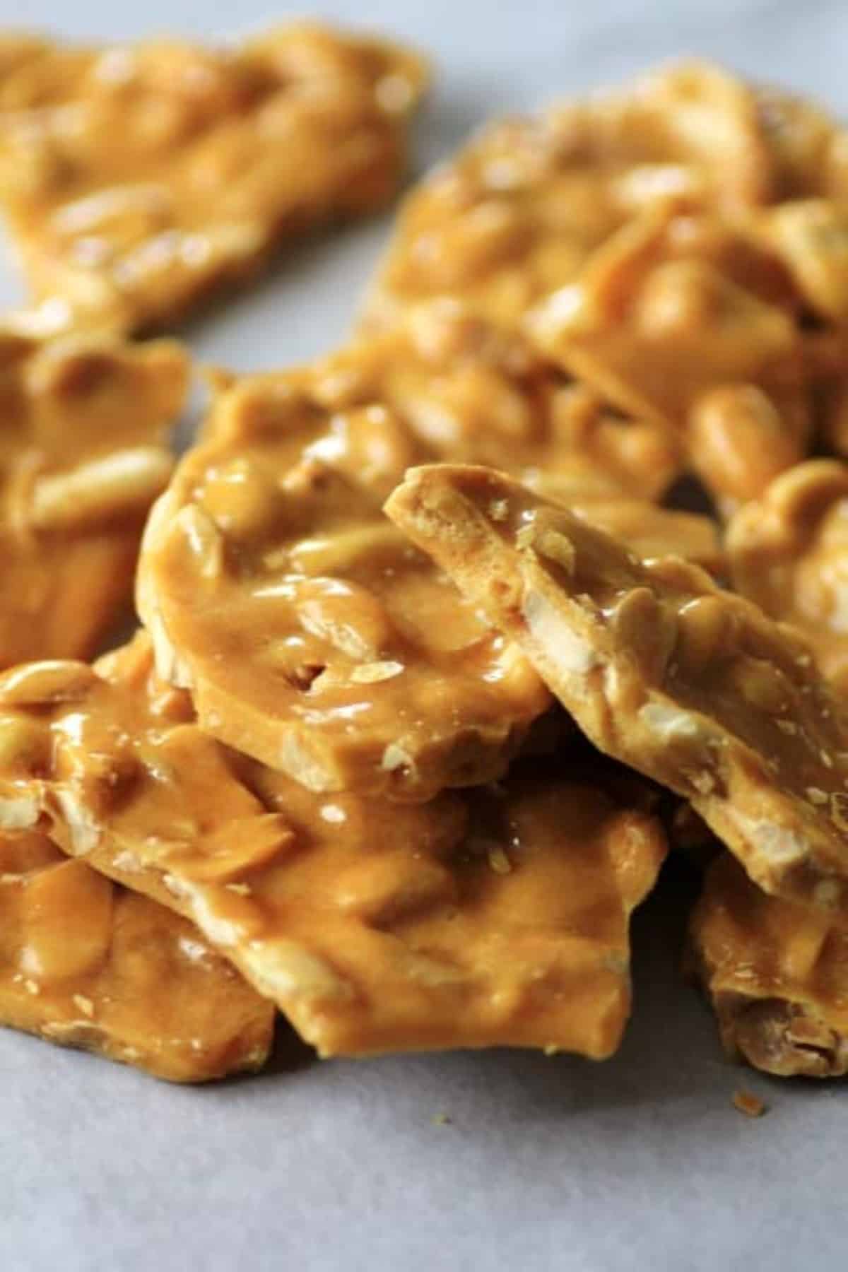 Peanut Brittle pieces stacked on a piece of parchment paper.