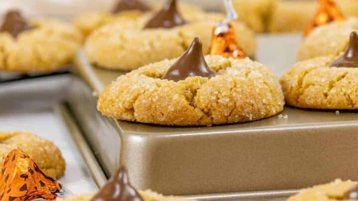 Peanut Butter Blossom cookies scattered about and some on top of over turned cookie sheets.