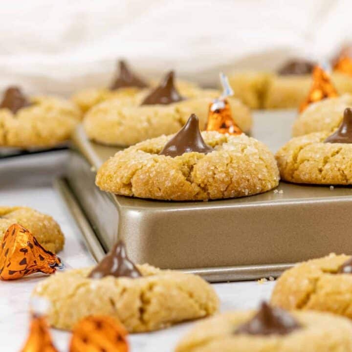 Peanut Butter Blossom cookies scattered about and some on top of over turned cookie sheets.