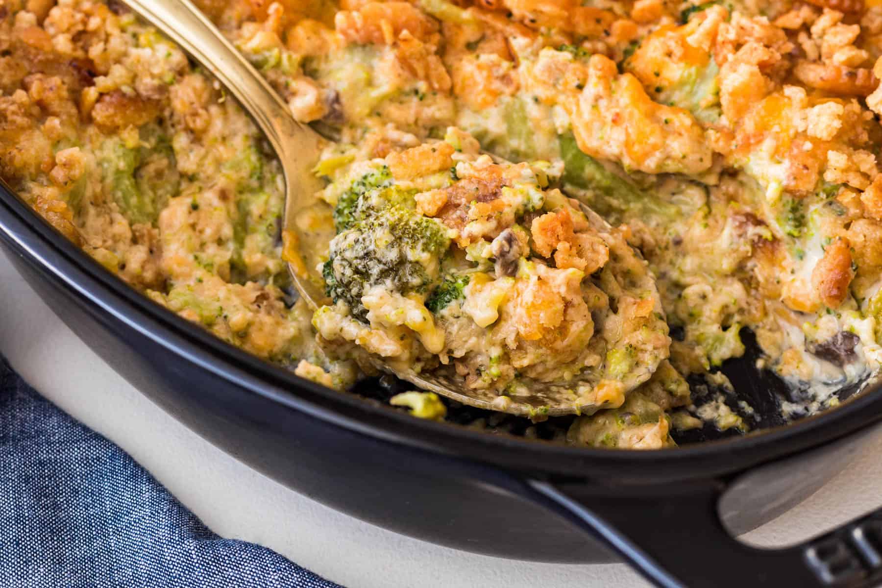 Horizontal photo of a close-up shot of broccoli casserole being served on a spoon. 