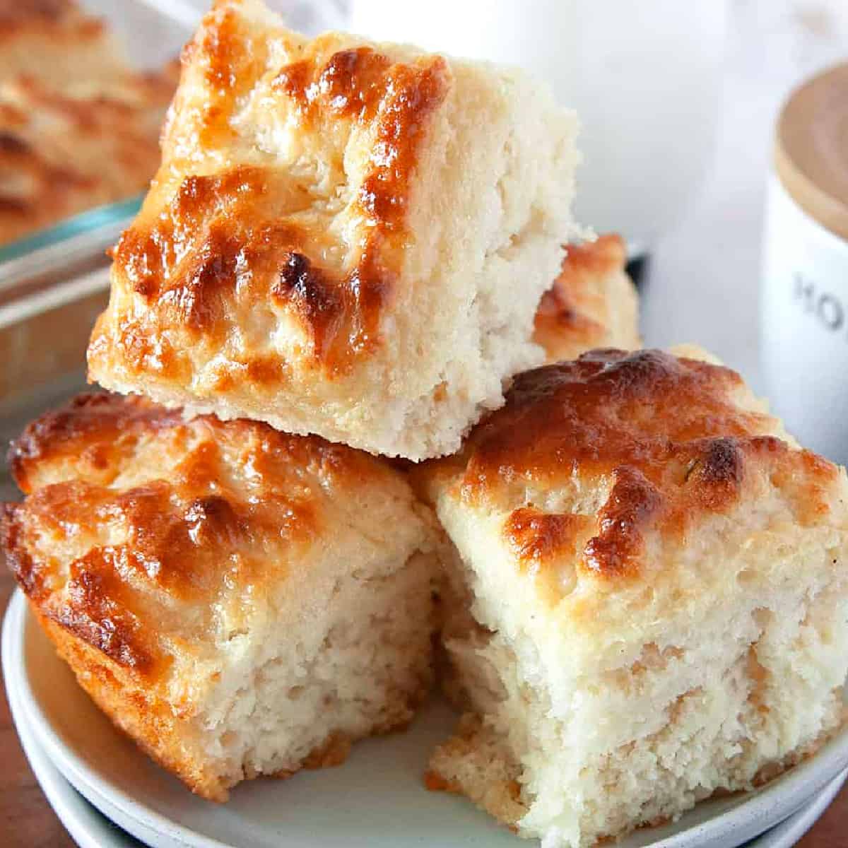 Biscuits stacked on each other on a plate showing their buttery golden brown tops. 