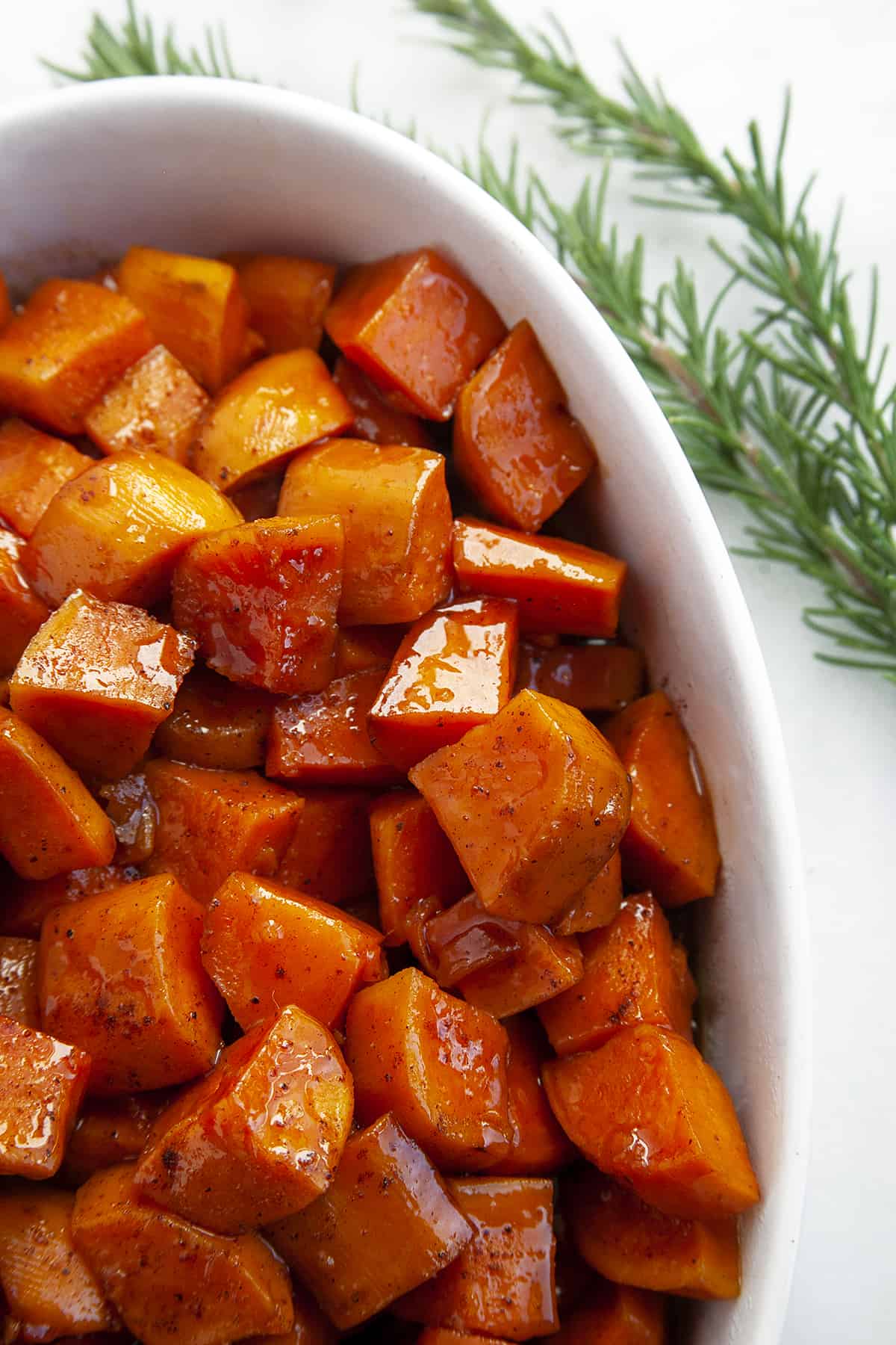 Overhead shot of candied yams in an oval white casserole dish. 