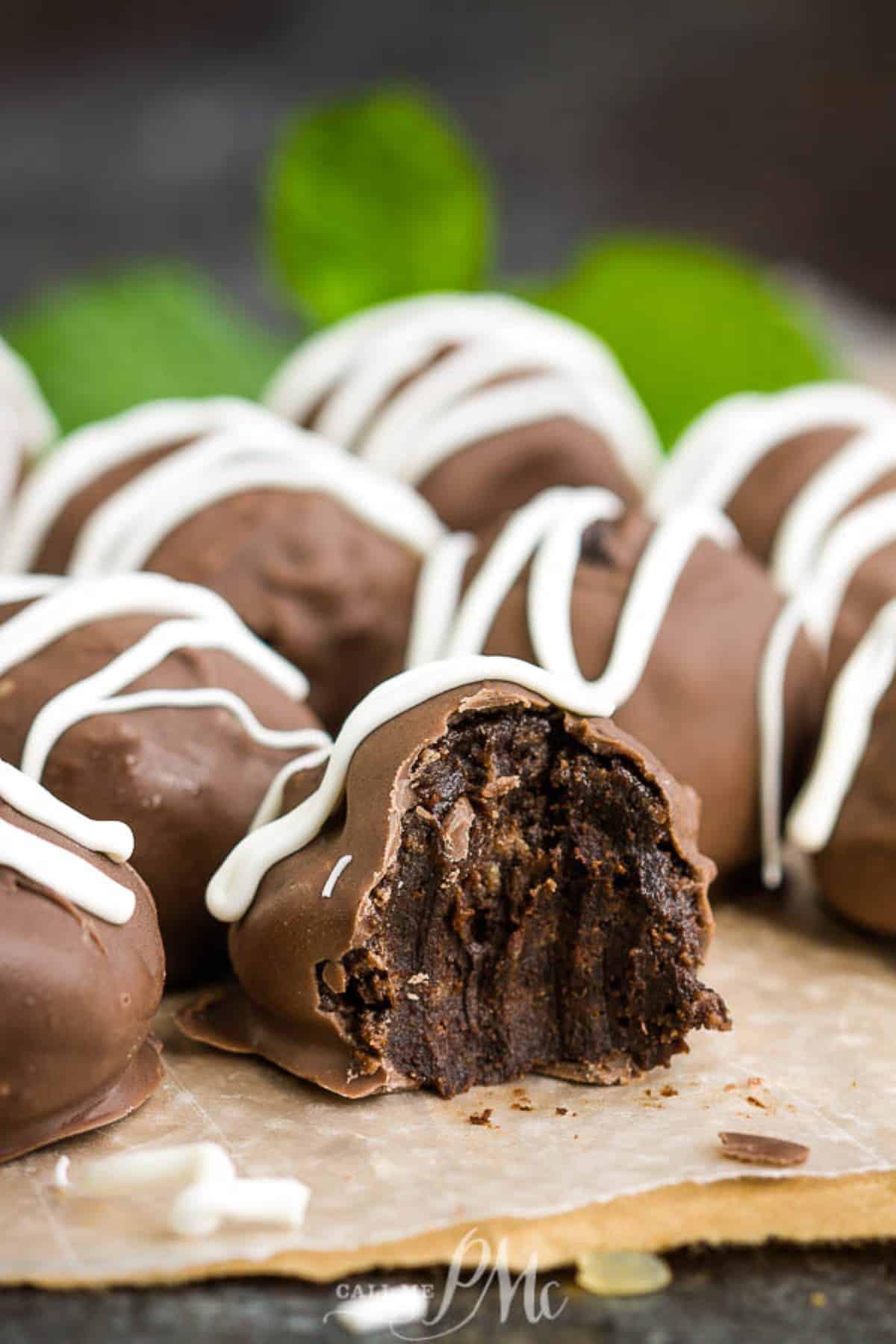 Cream Cheese Brownie Truffles on a brown paper bag, one with a bite taken out.