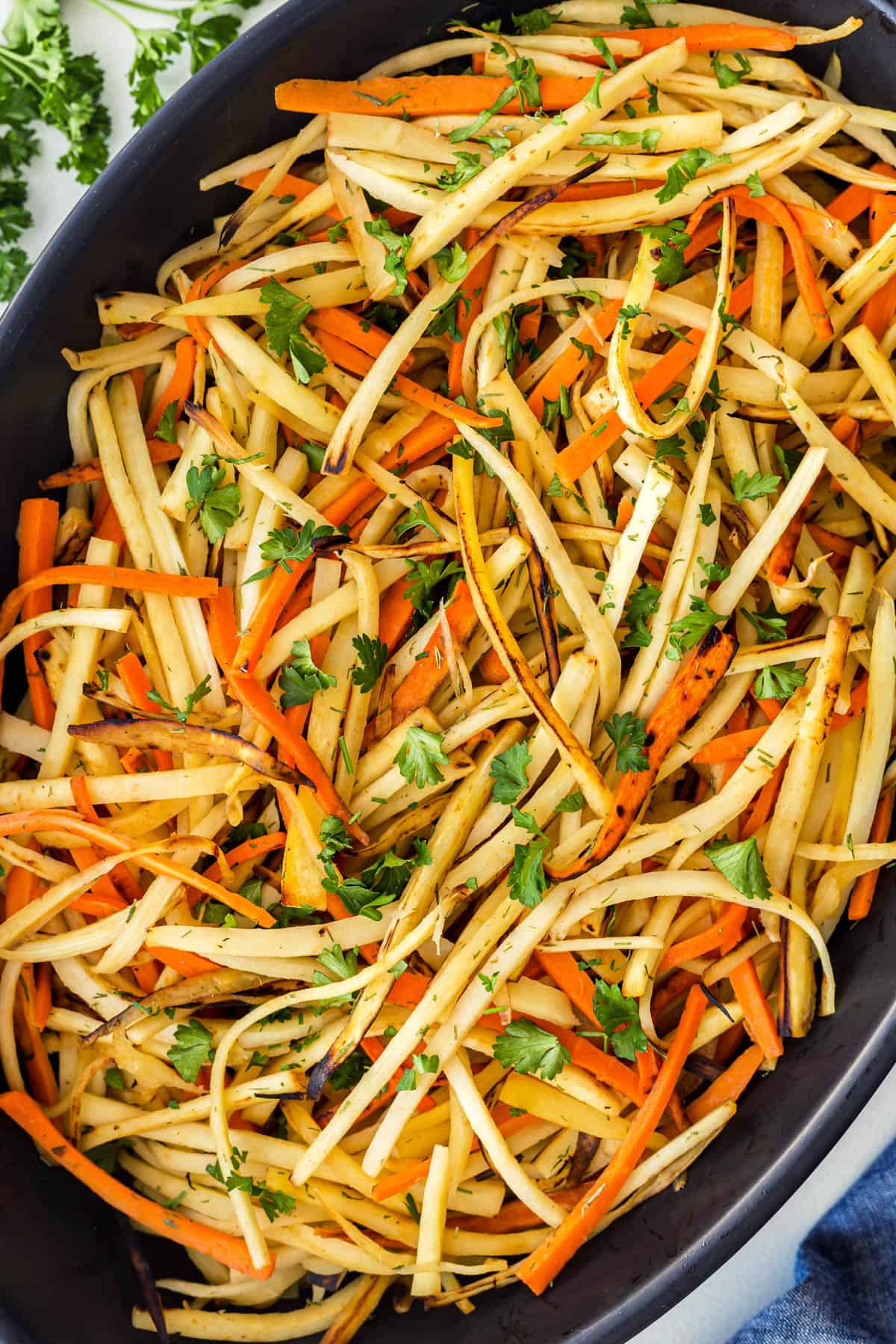 Close-up of matchstick pan-fried carrots and parsnips in a casserole. 