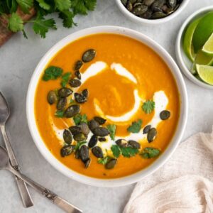 Overhead shot of pumpkin curry soup in a bowl with cilantro and pepitas on top.