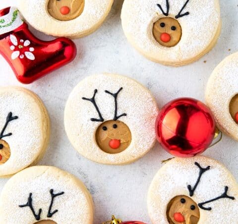 Overhead shot of Reindeer Linzer Cookies with Christmas ornaments.