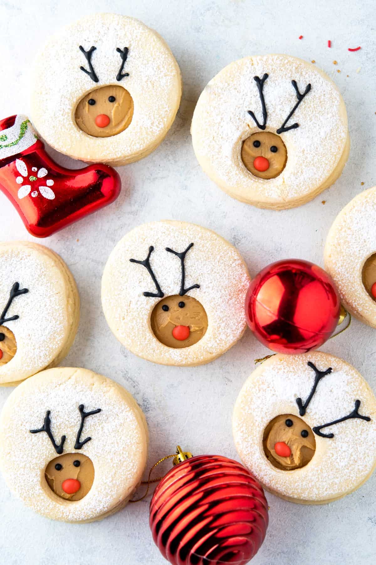 Overhead shot of Reindeer Linzer Cookies with red ornaments in between. 