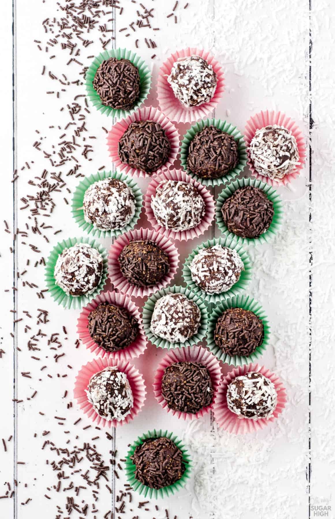 No-Bake Chocolate Rum Balls served in small paper cupcake wrappers on a white tabletop.