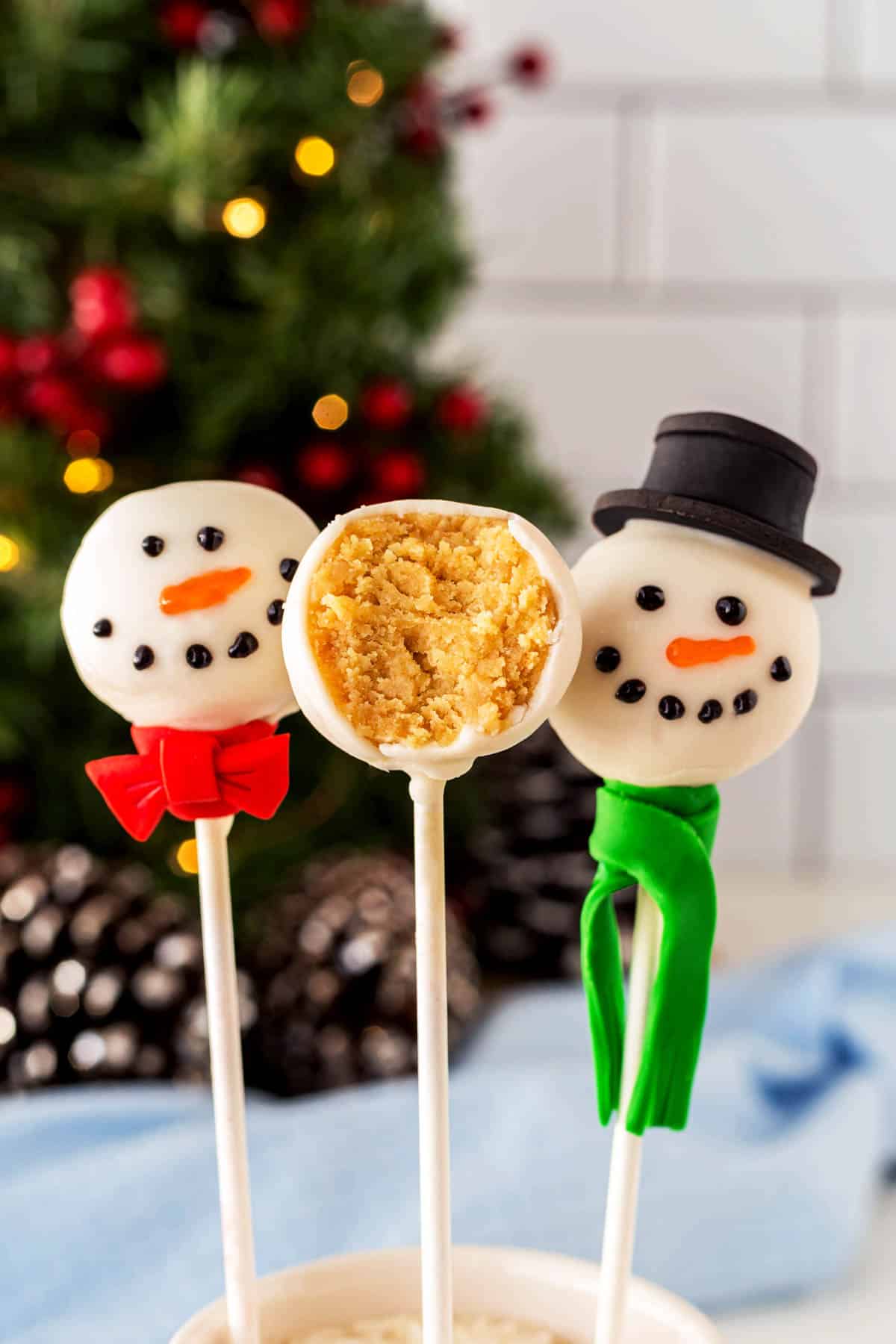 Three snowman cake pops but the middle one is half eaten. 
