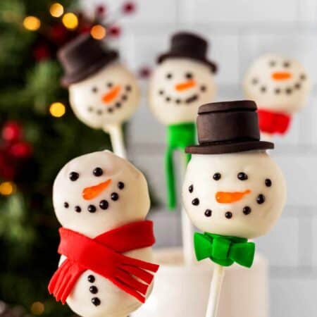 Two Snowman Cake Pops close-up with others in the background.