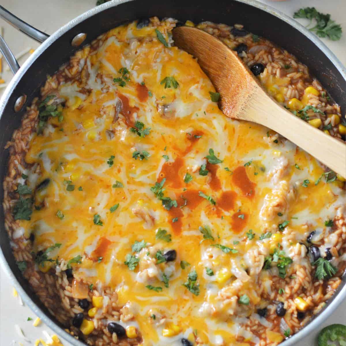 Square overhead photo of skillet enchilada rice with a wooden spoon in it. 