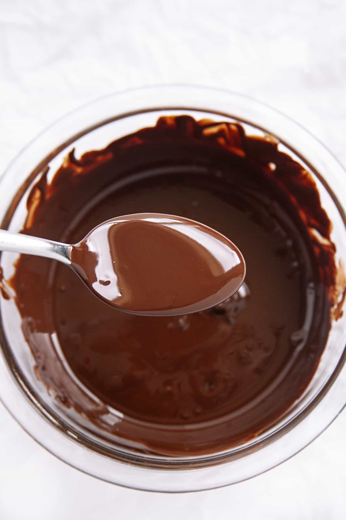 Showing a spoonful of chocolate from a bowl of of melted chocolate. 