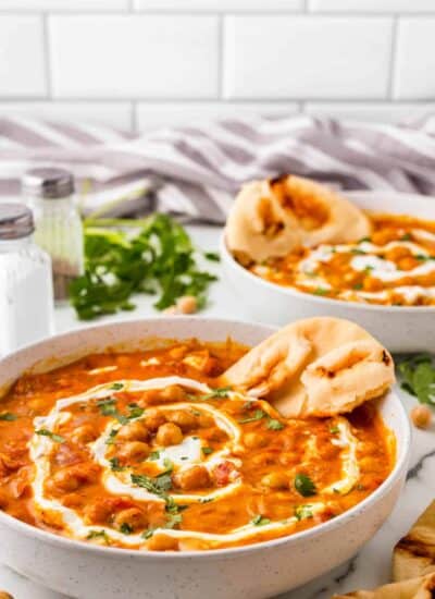 Bowls of chickpea curry with naan bread stuck in.